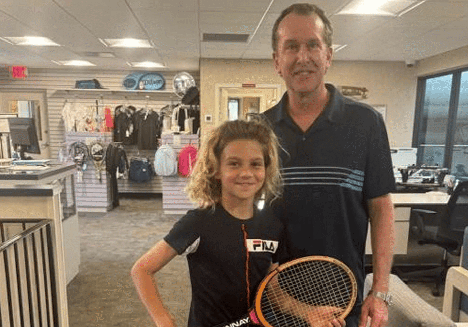 Man and a girl standing next to each other, both of them holding tennis rackets